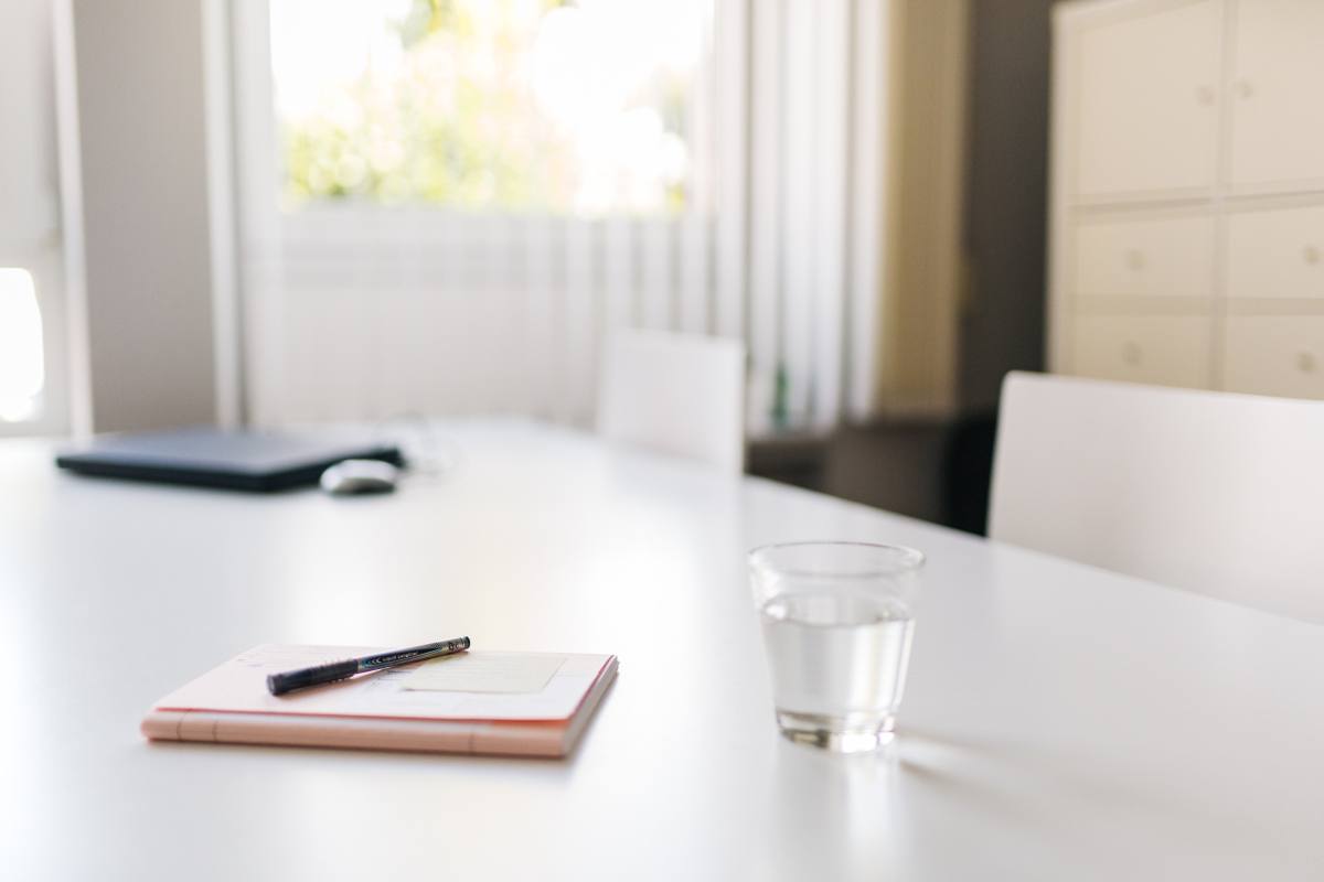 Ruhiger Schreibtisch mit Notizen, Wasserglas und Laptop für das Beratungsgespräch bei SprechWerk